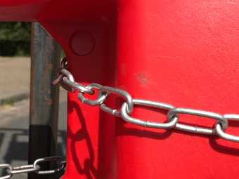 silver chain on a red bollard road block 