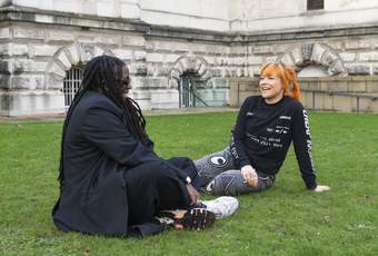 Two people talking while sitting on grass