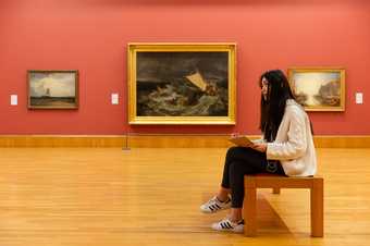 A visitor sitting and drawing in a gallery