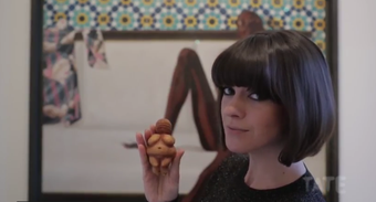 dawn o' porter looks at the camera holding a small sculpture of a woman